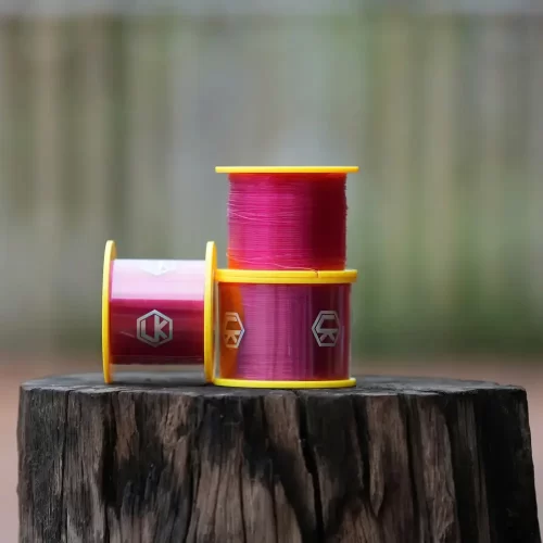 Dây câu cước LK bộ ba cuộn cước màu hồng xếp chồng lên nhau trên khúc gỗ